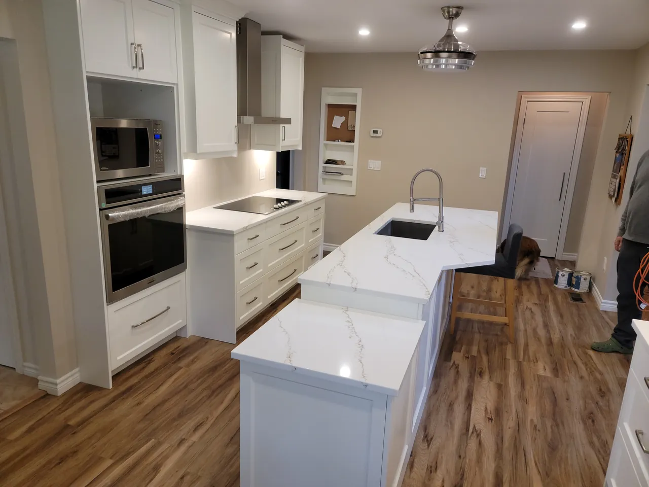 White kitchen with a quartz waterfall peninsula and built in wall ovens