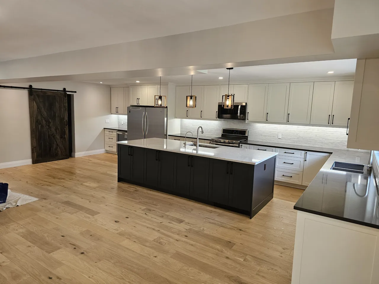 Custom kitchen with a dark island, white shaker cabinets and pendant lights