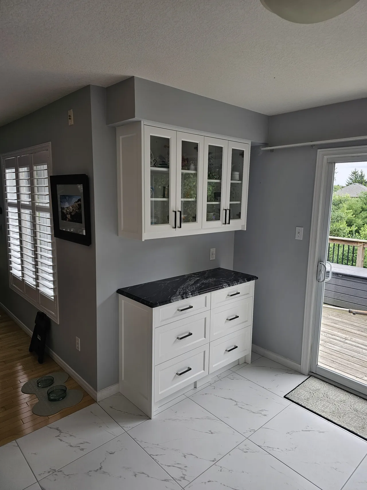 White built in hutch with glass front uppers and a dark stone top