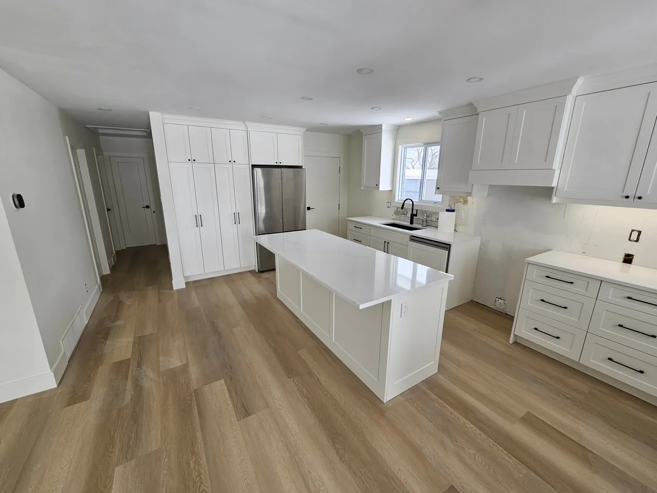 White kitchen with a large island and full height pantry cabinets
