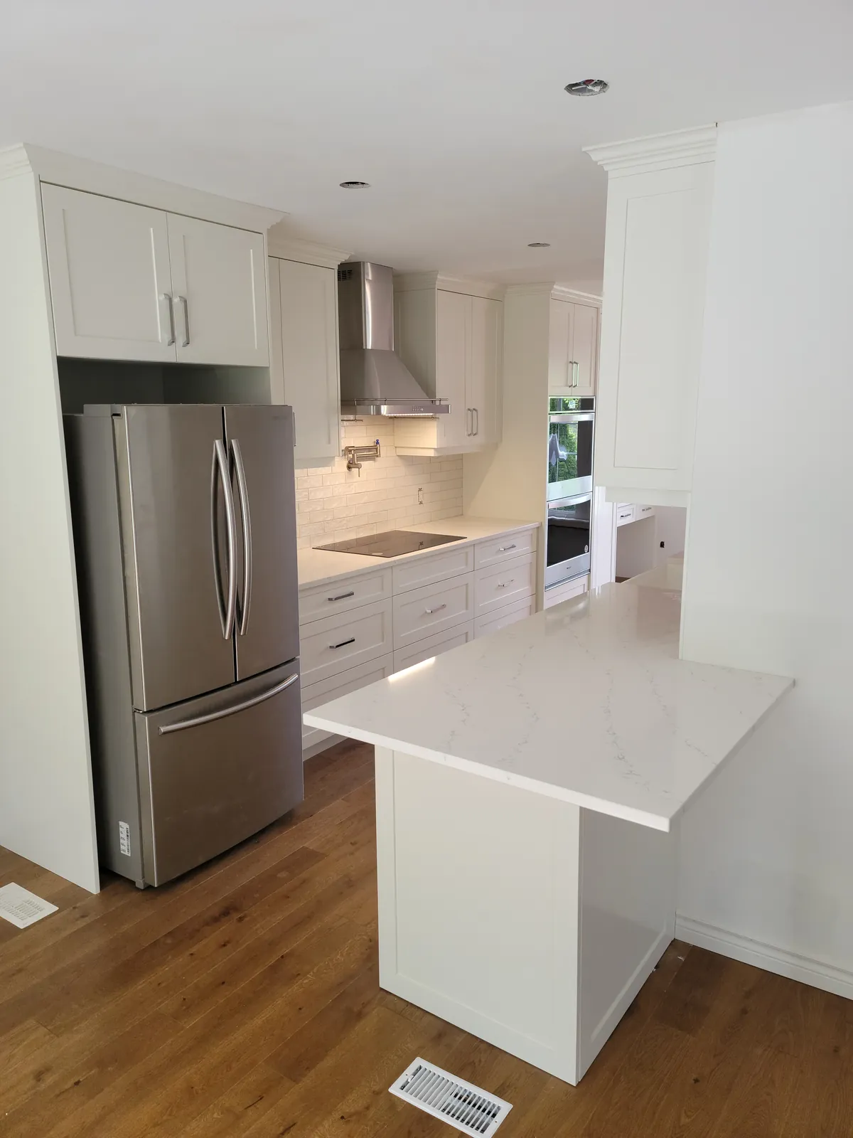 White shaker kitchen with a quartz peninsula and stainless steel appliances